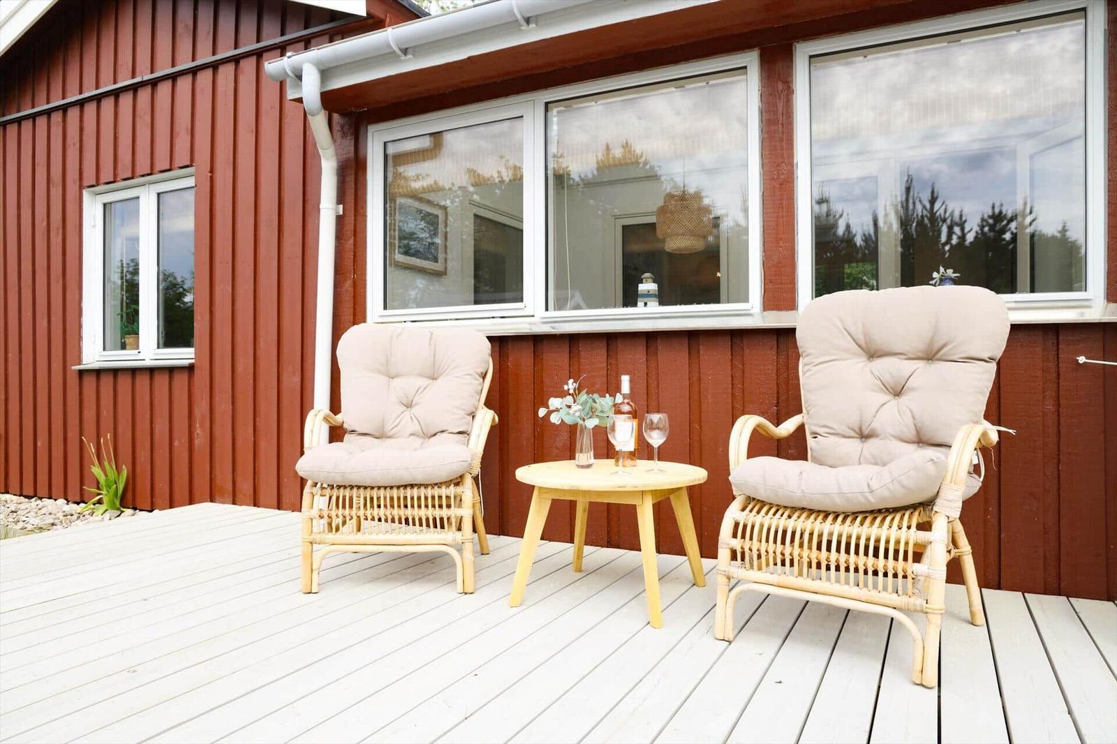 Terrasse mit zwei Rattan-Stühlen und einem kleinen Tisch.