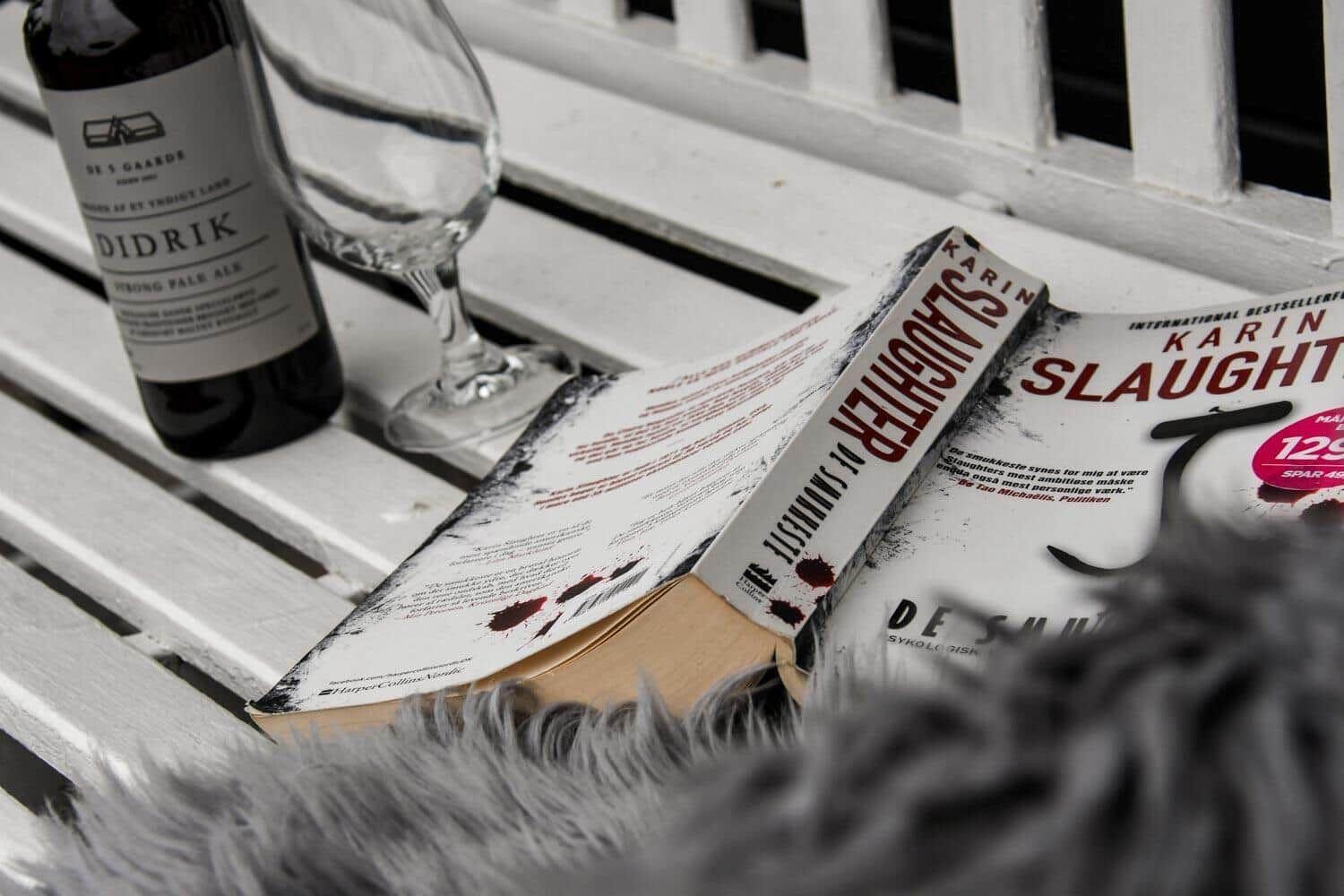 Ein Buch und eine Flasche stehen auf einer weißen Bank.