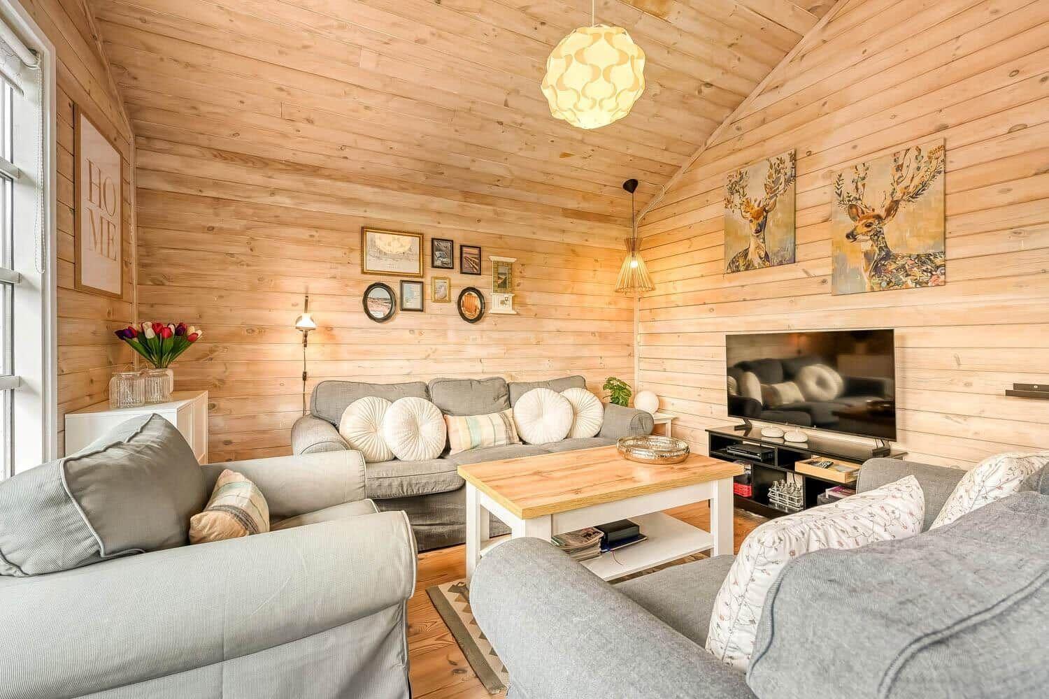 Wohnzimmer mit Holzwand, Sofa, Couchtisch und Fernseher.