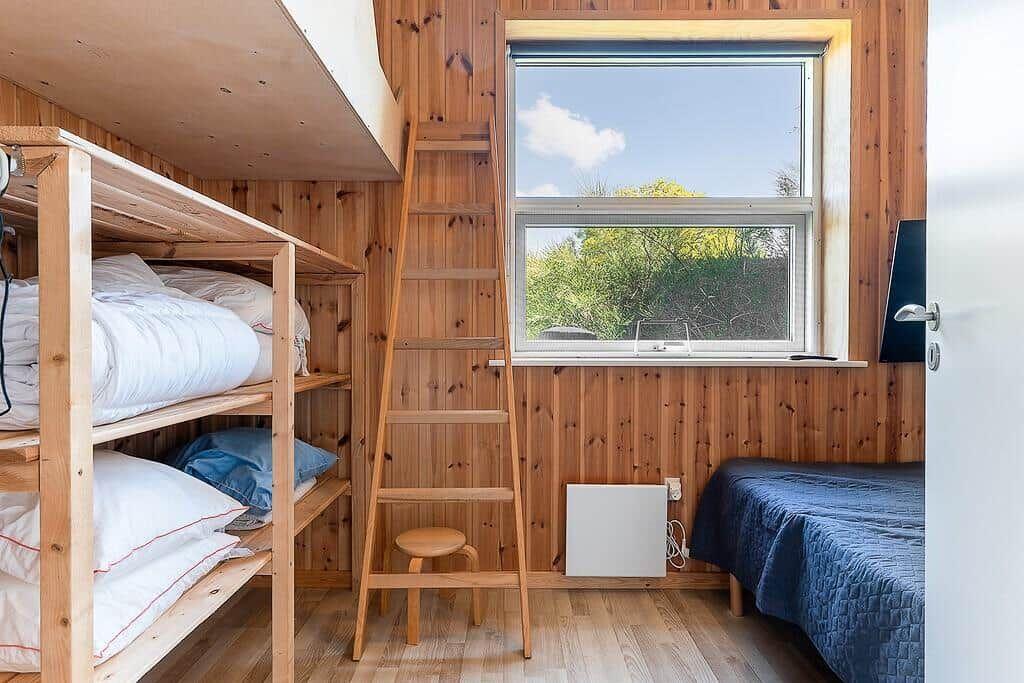 Room with daybed, ladder, and window overlooking greenery.