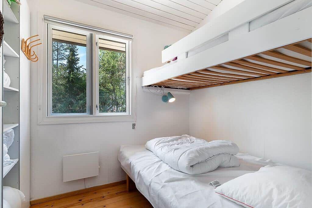 Room with double bed, loft bed, and window to the forest