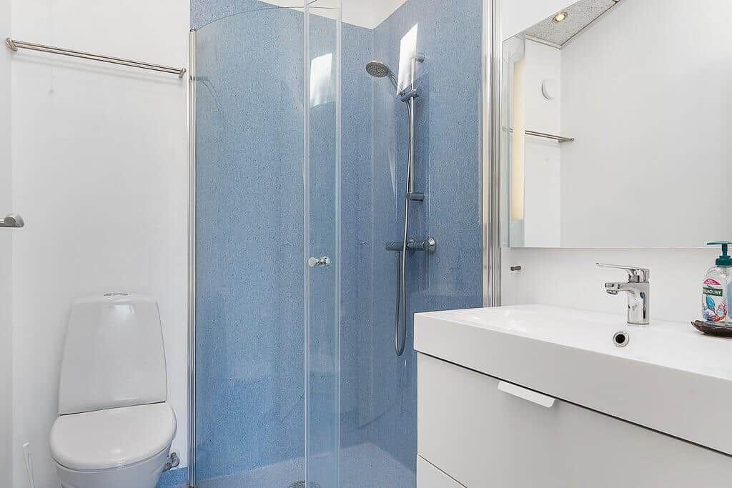 Bathroom with shower, sink and toilet. Tiles in blue and white.