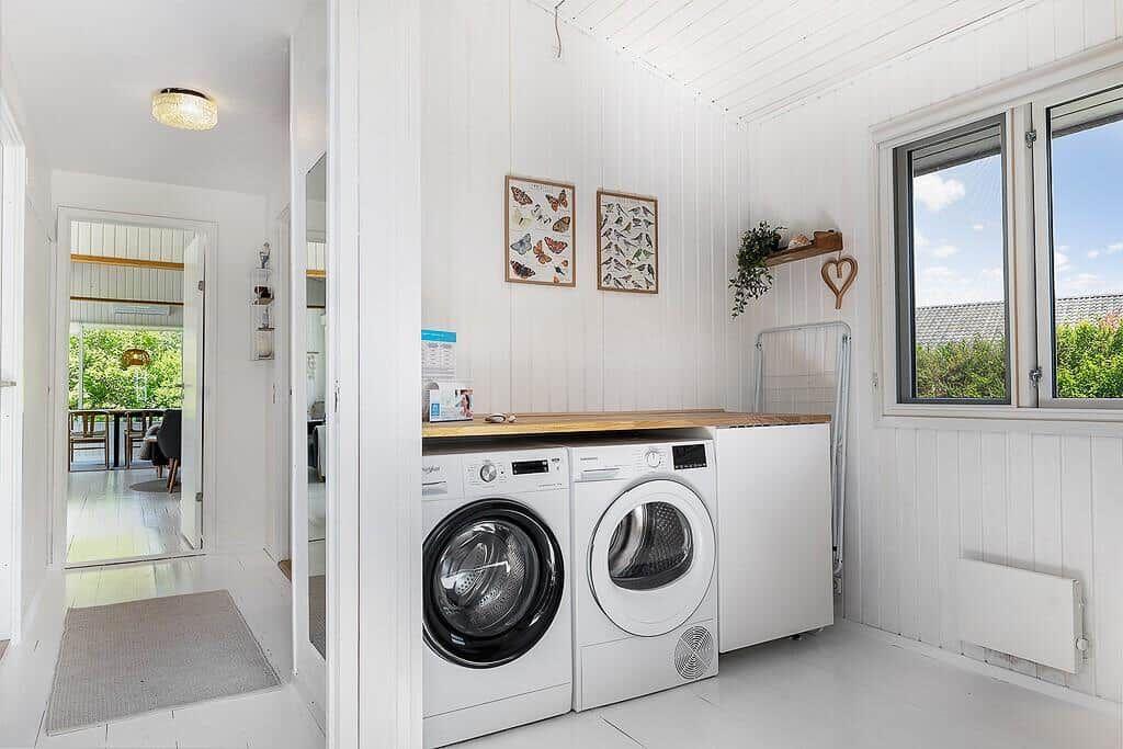 Washing room with washing machine, dryer, and window.