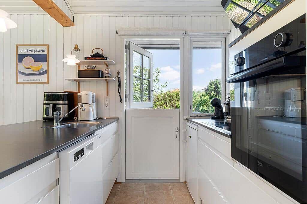 Kitchen with white cabinets, stainless steel sink, and view of green outdoor areas.