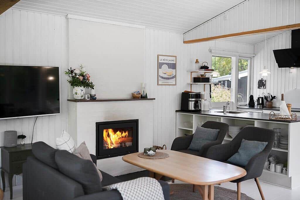 Living area with fireplace, TV, and dining space. Kitchen with countertop and window.