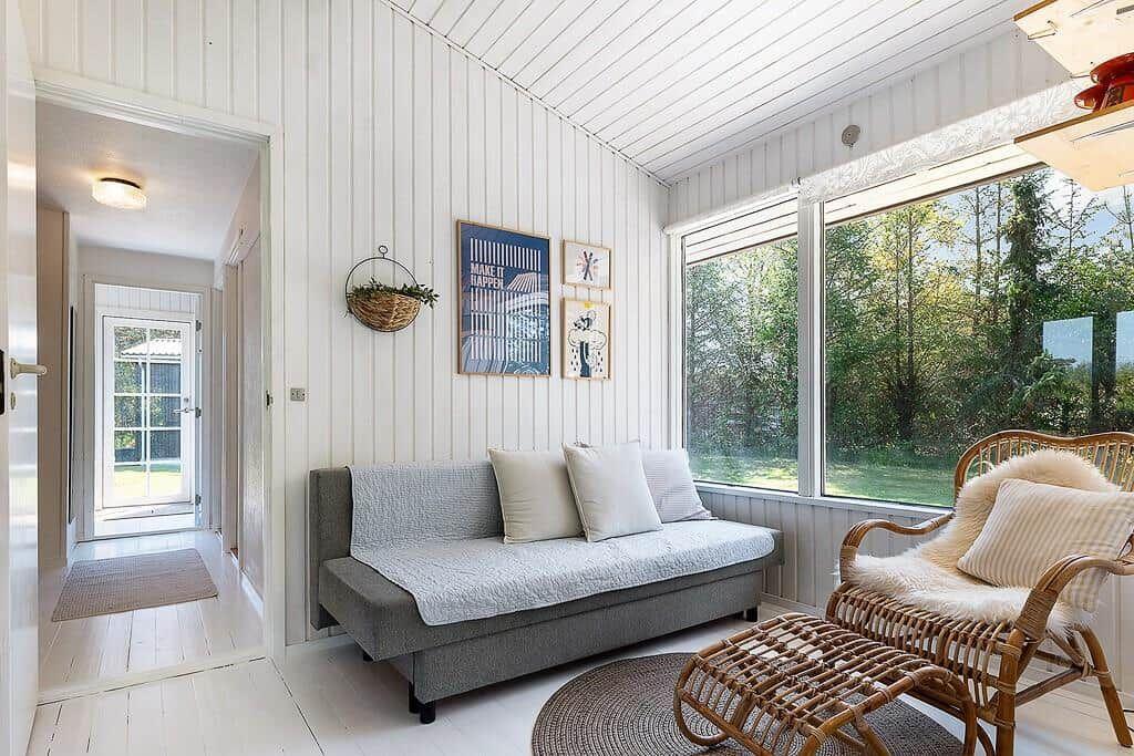 Living area with sofa, rattan chair, and view of the garden.