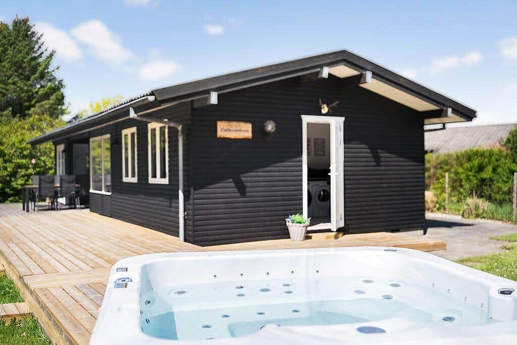 Black wooden house with terrace and outdoor hot tub.