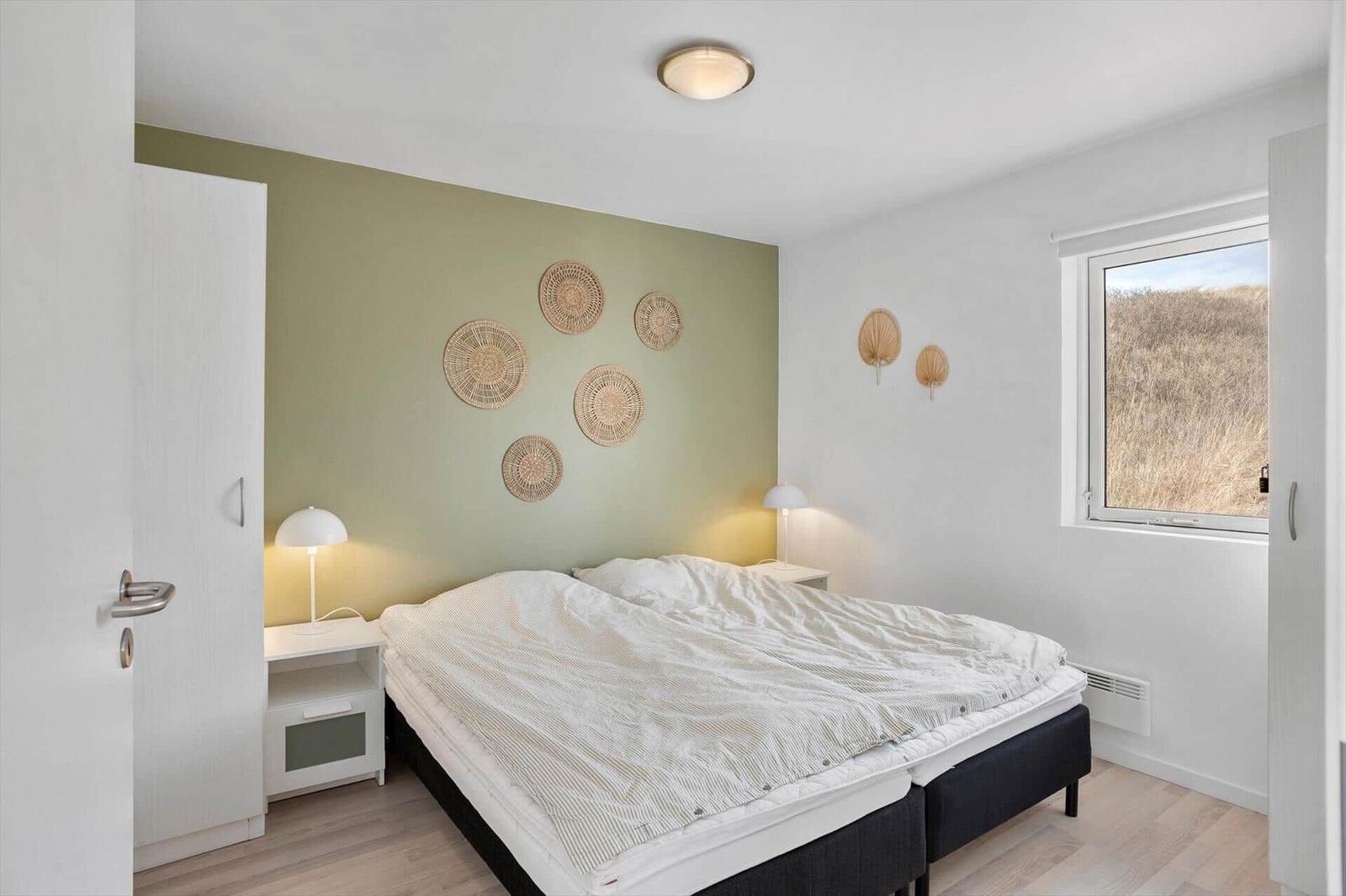 Schlafzimmer mit Doppelbett, Nachttischen und Fenster zum Blick auf die Landschaft.
