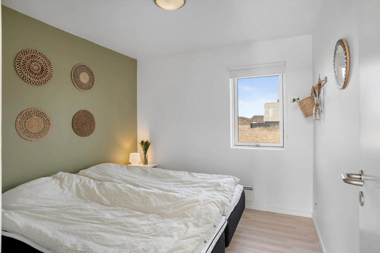 Schlafzimmer mit Bett, Fenster und Wanddekoration.