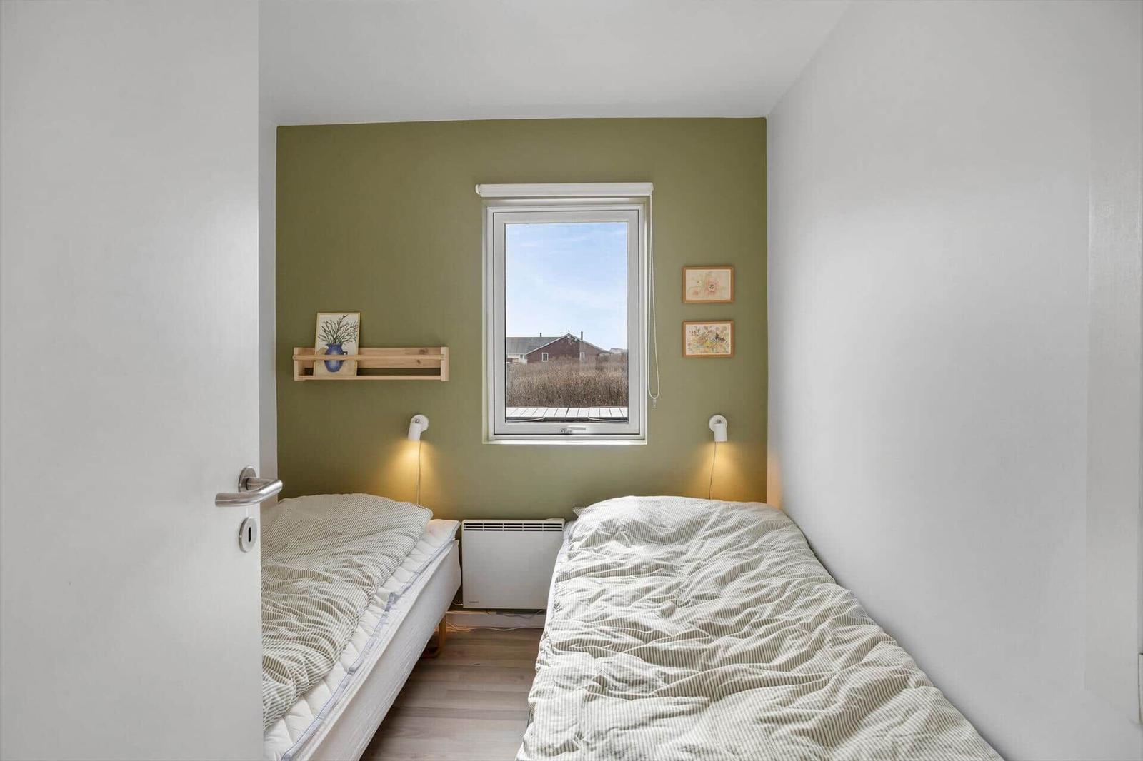 Zwei Betten gegenüberliegend, grüne Wand, Fenster mit Aussicht.