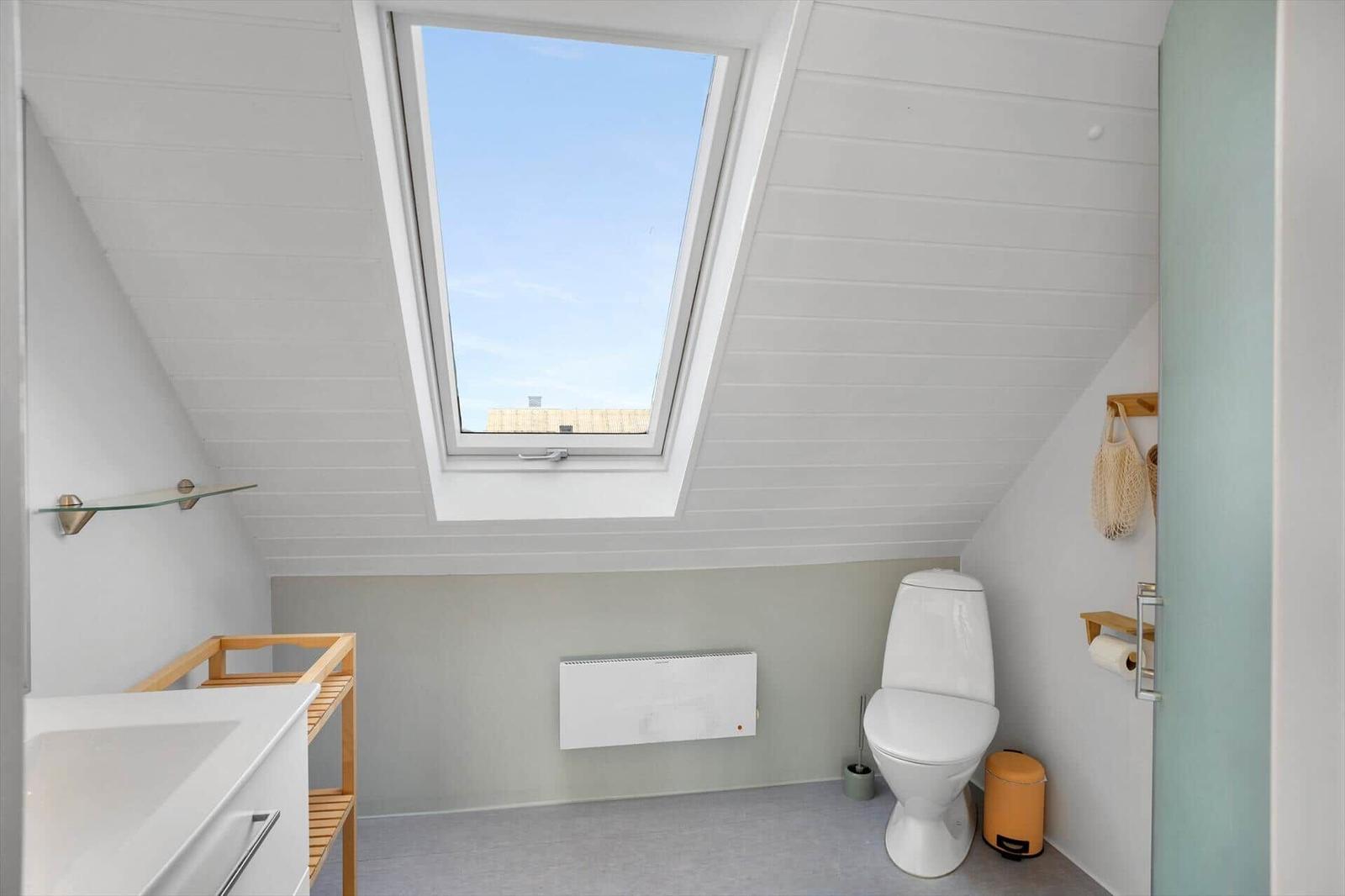 Badezimmer mit Dachfenster, Toilette und Waschbecken.