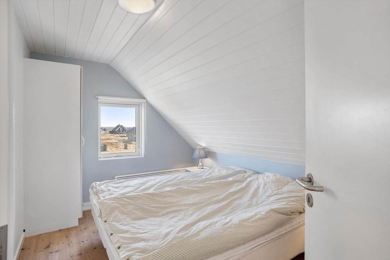 Schlafzimmer mit Dachschräge, Fenster und Bett.