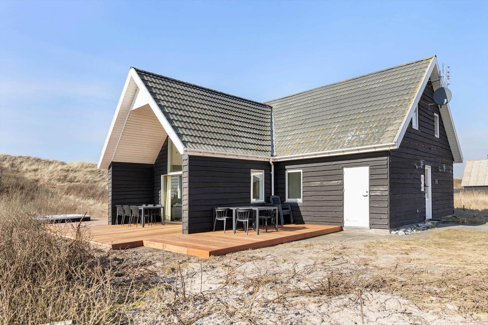 Moderne Strandhütte mit Terrasse, Gartenmöbeln und Dachgaube. Ideal für Urlaub an der Küste.
