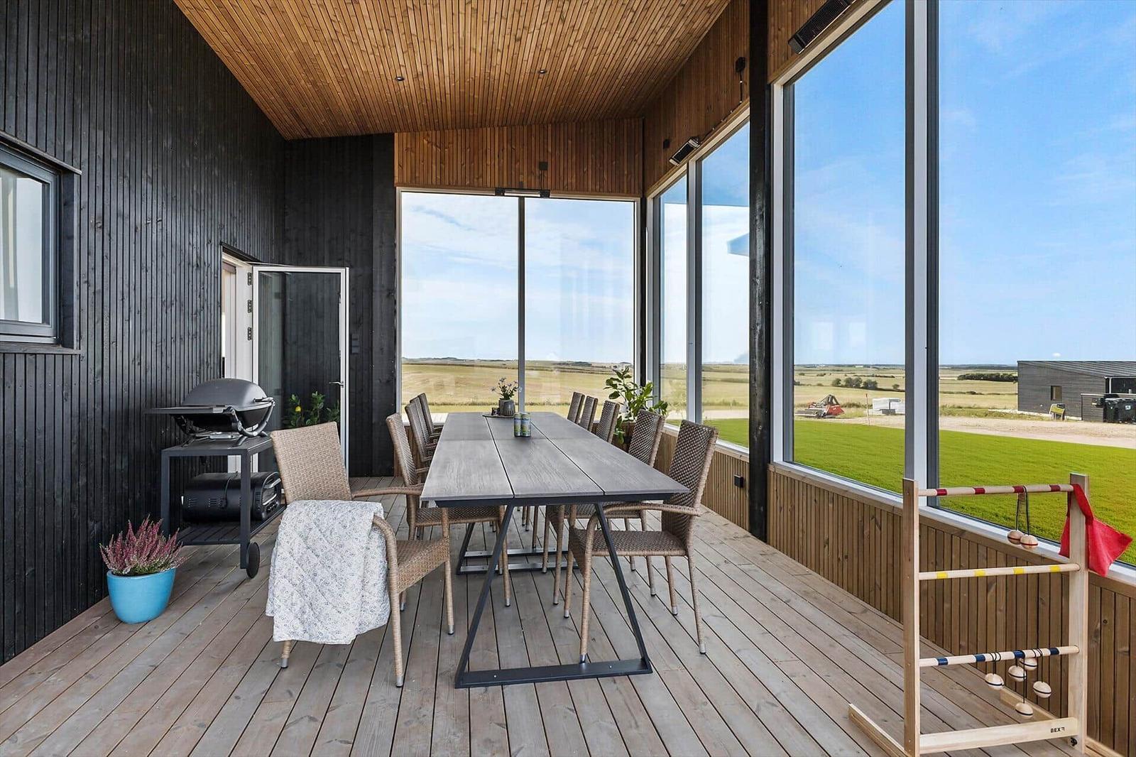 Terrasse mit Esstisch, Grill und Blick auf Felder.
