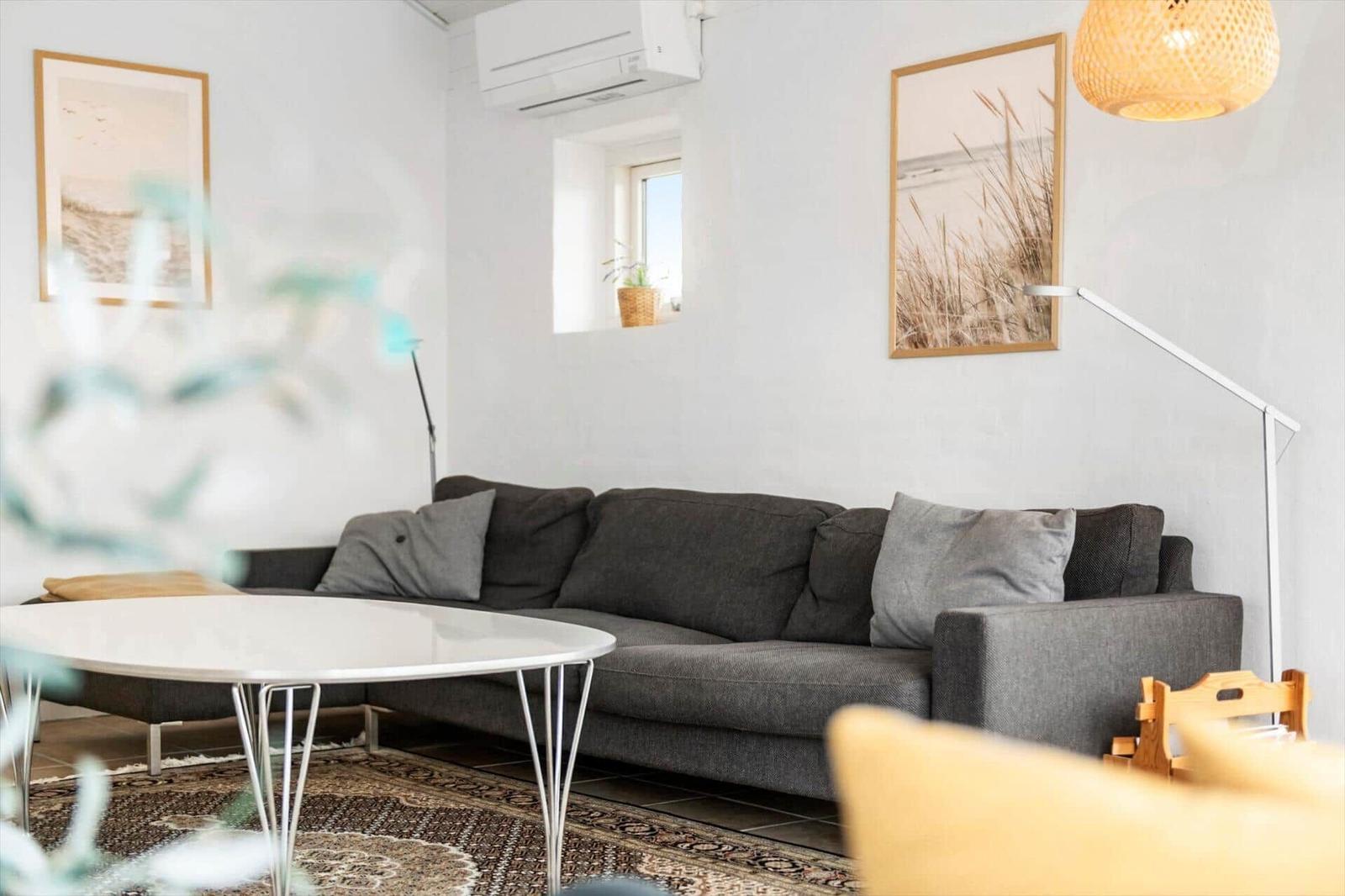 Ein Wohnzimmer mit grauem Sofa, runden Tisch und Wandbildern.