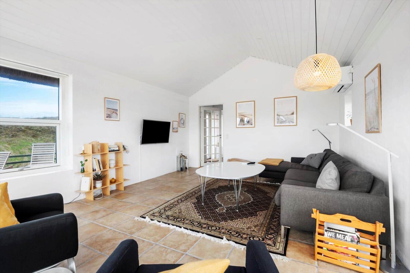 Wohnzimmer mit Sofa, Tisch und Fensterblick auf Grünland.