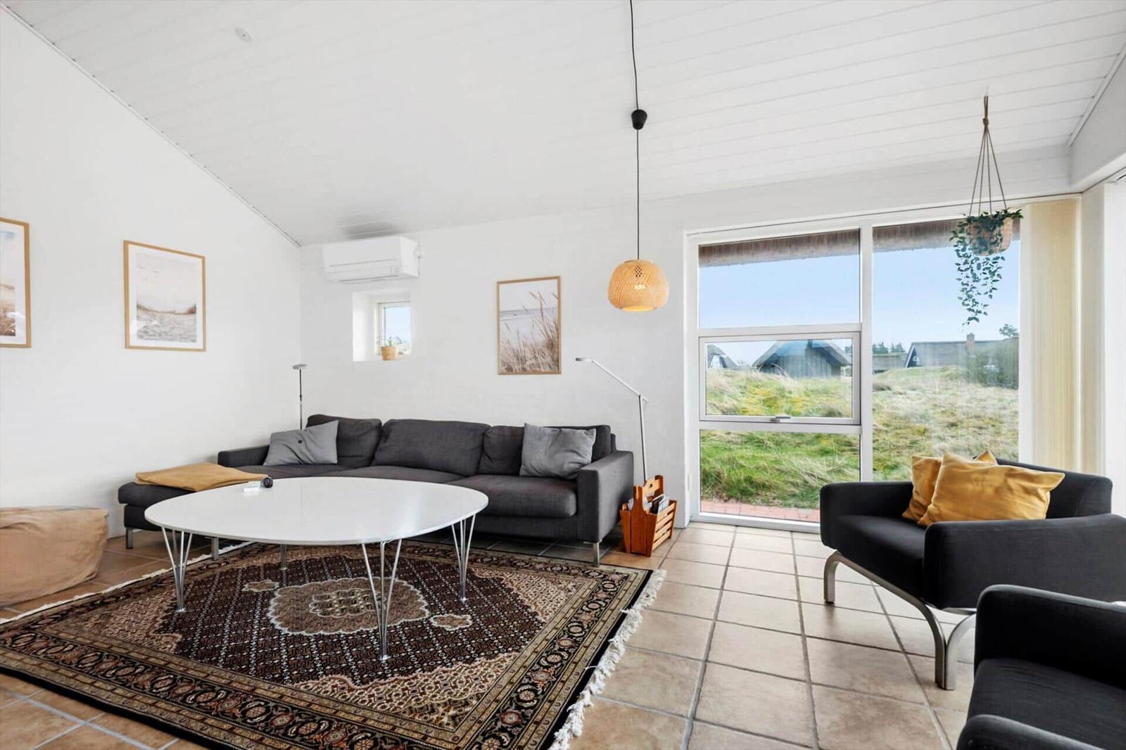 Wohnzimmer mit Sofa, Tisch und Blick auf Grasland.