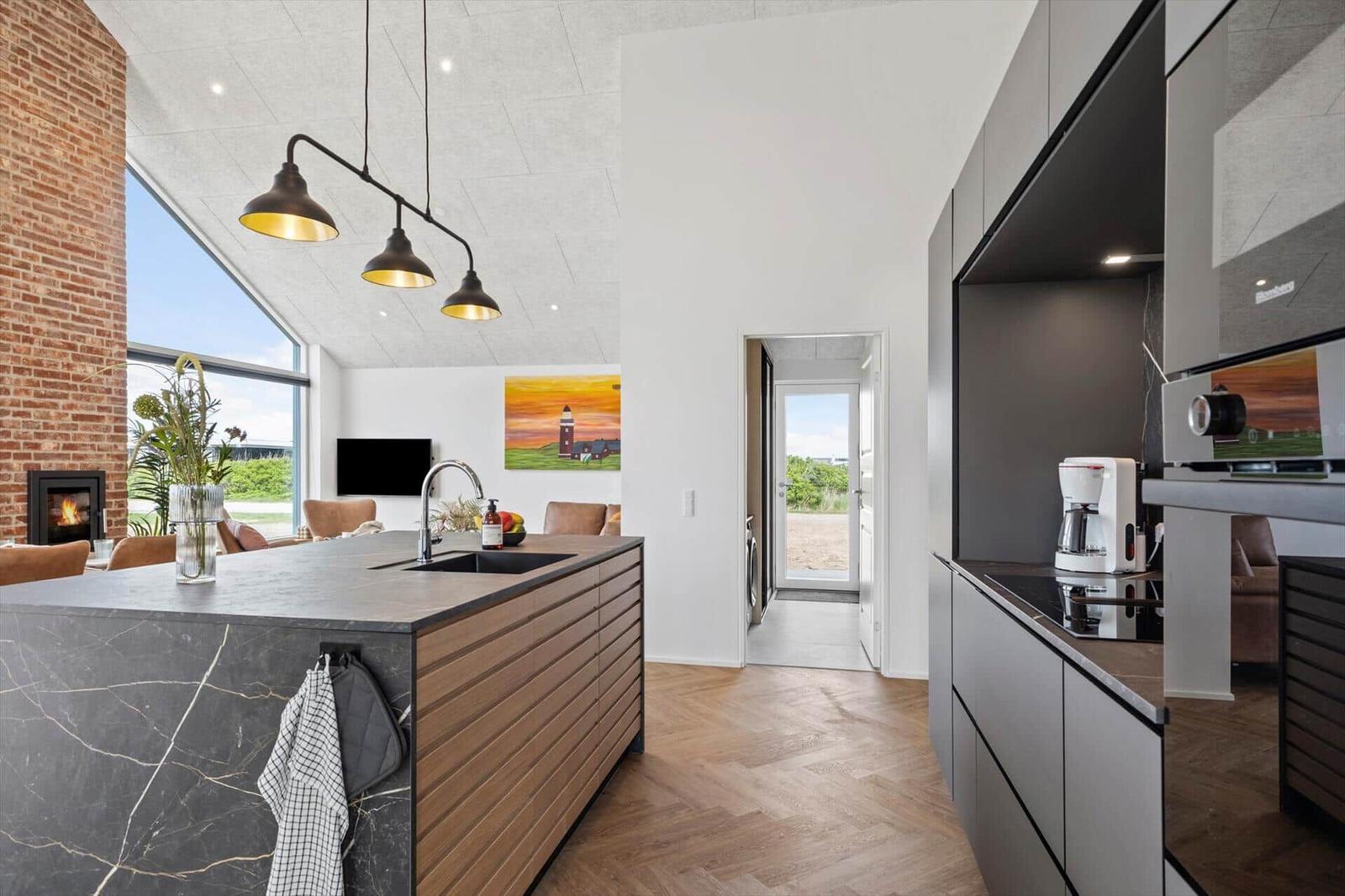 Küche mit Insel, Backofen und Blick auf Wohnbereich mit Kamin.