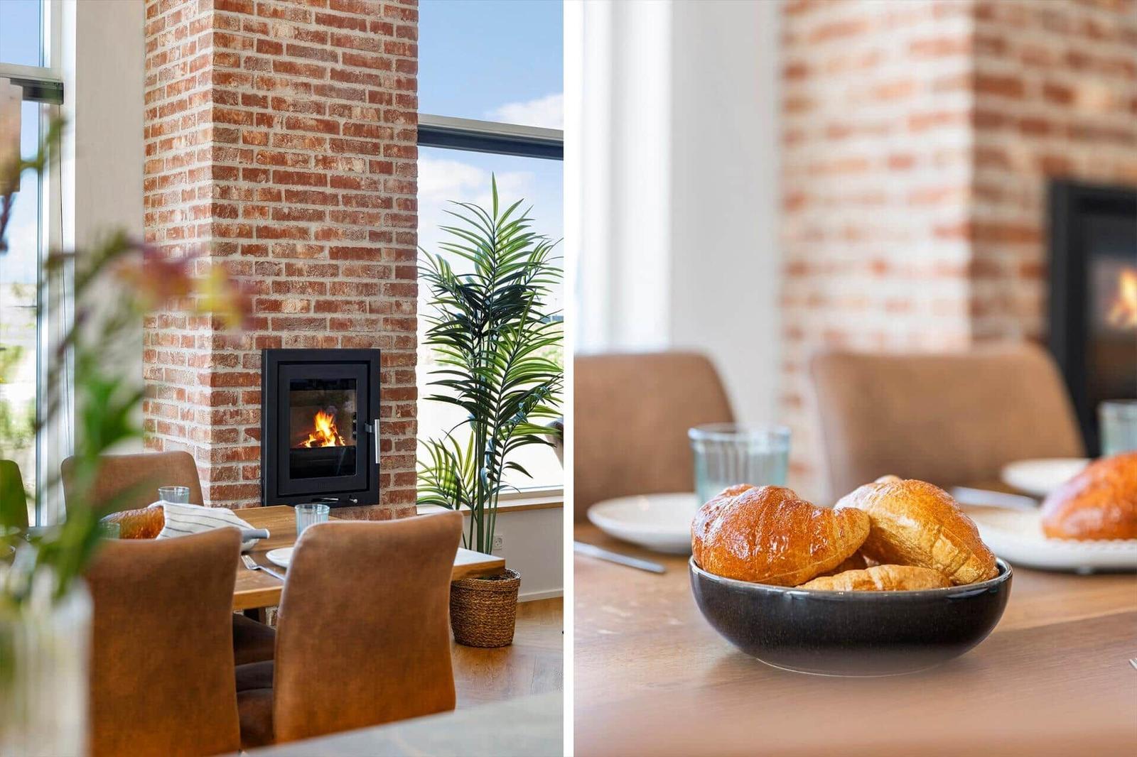 Esszimmer mit Kamin, Tisch und Stühlen sowie einer Pflanze. Auf dem Tisch stehen Croissants.