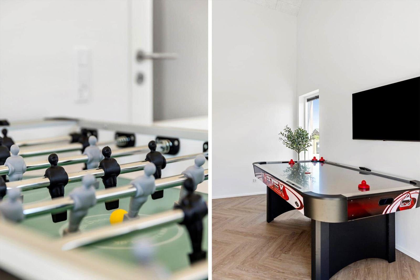 Fußballtisch und Air-Hockey-Tisch in einem Spielzimmer mit Holzboden und Wandfernseher.