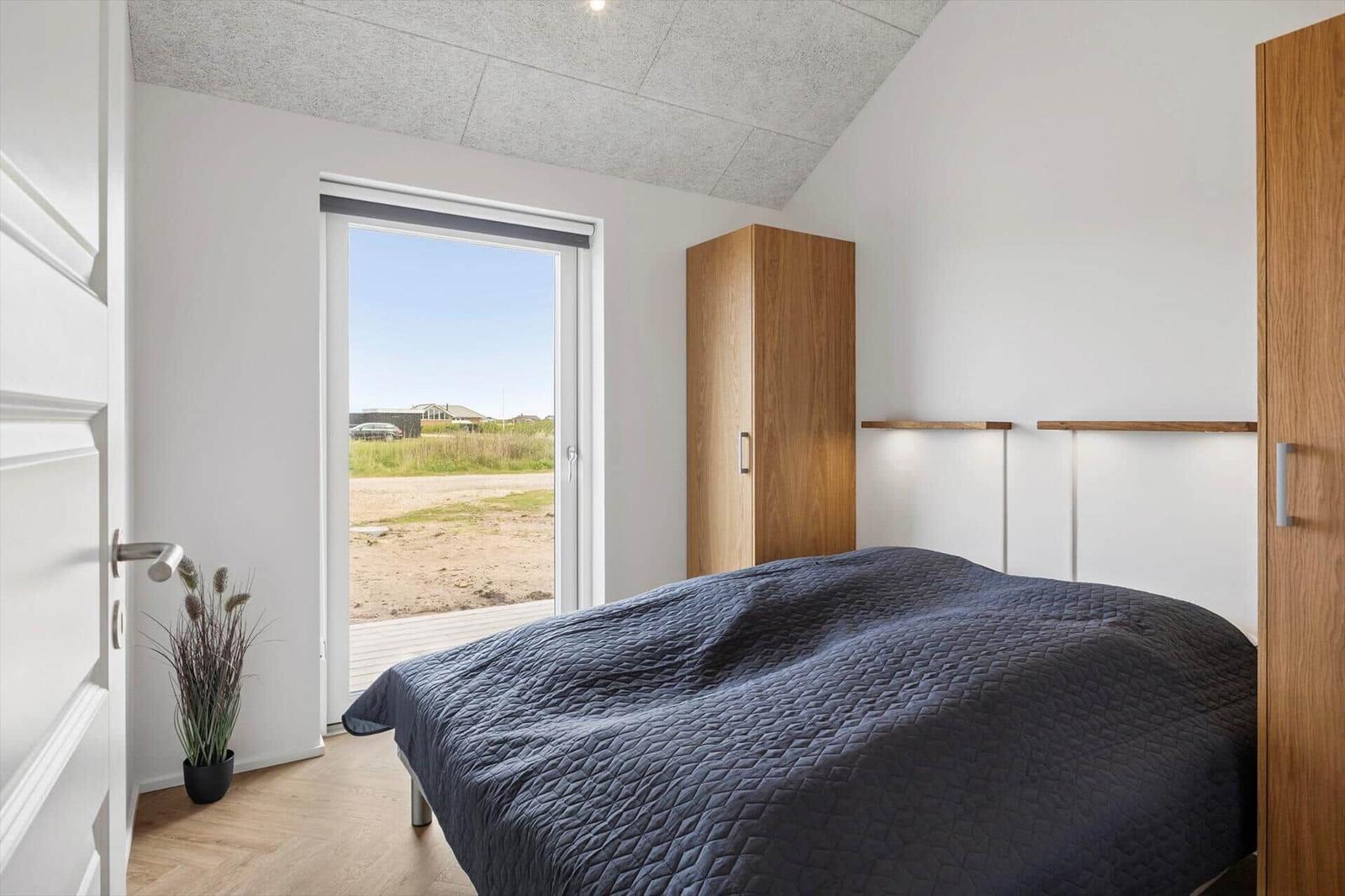 Schlafzimmer mit Bett, Schrank und Blick auf Außenbereich.