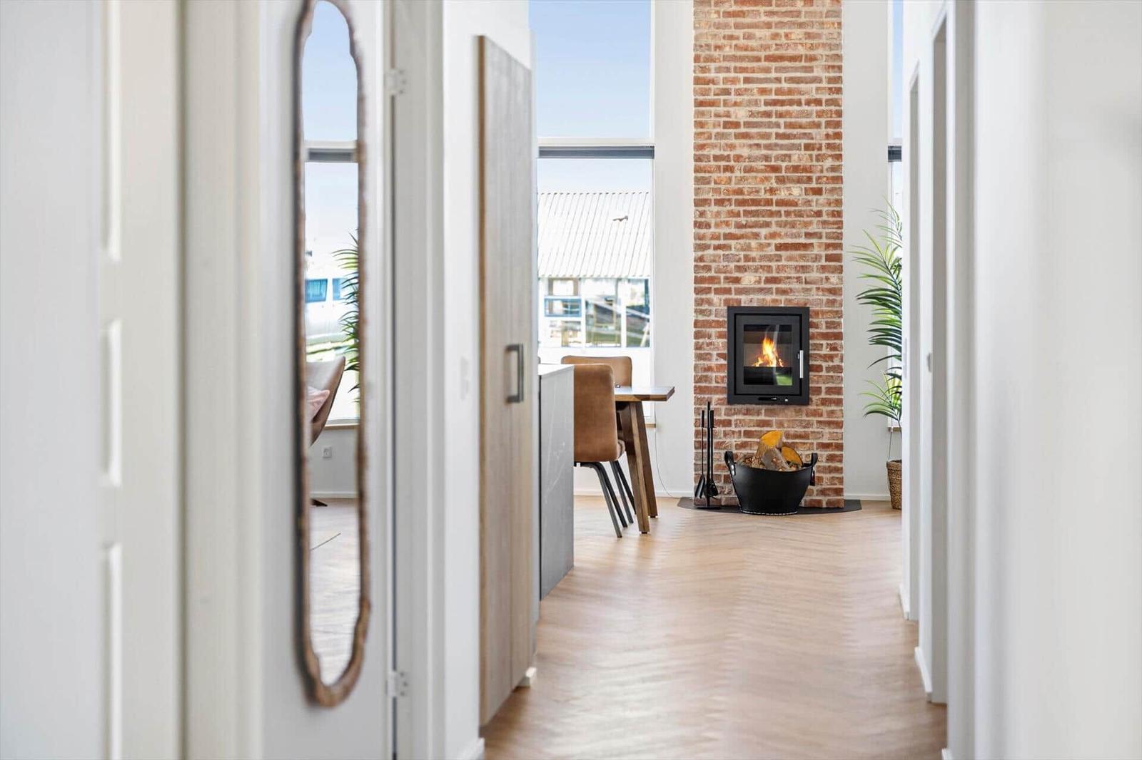 Haus mit Kamin, Holzfußboden und Blick auf Terrasse.
