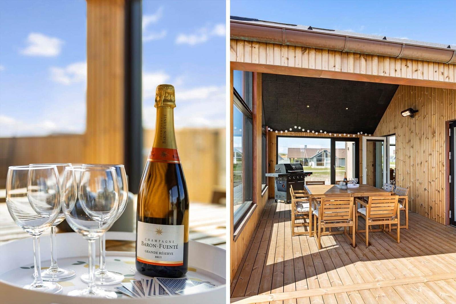 Bottle of champagne and glasses on tray. Wooden terrace with table, chairs, and grill.