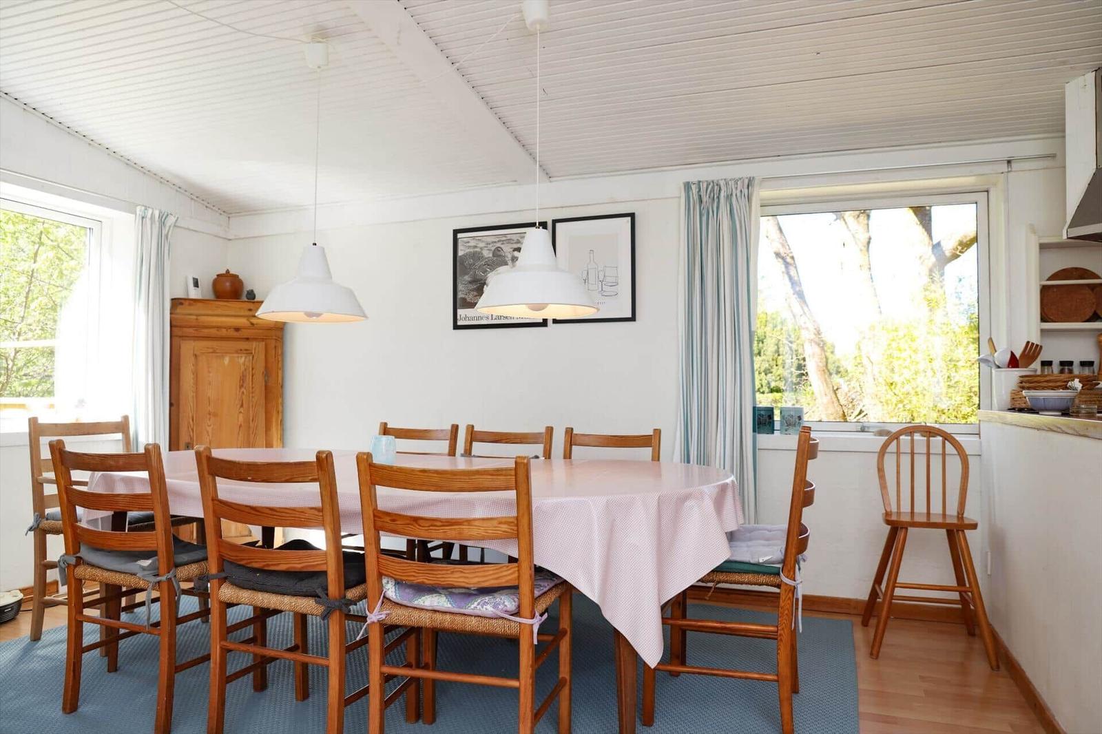 Esszimmer mit Holztisch, Stühlen und Fensterblick auf Bäume.