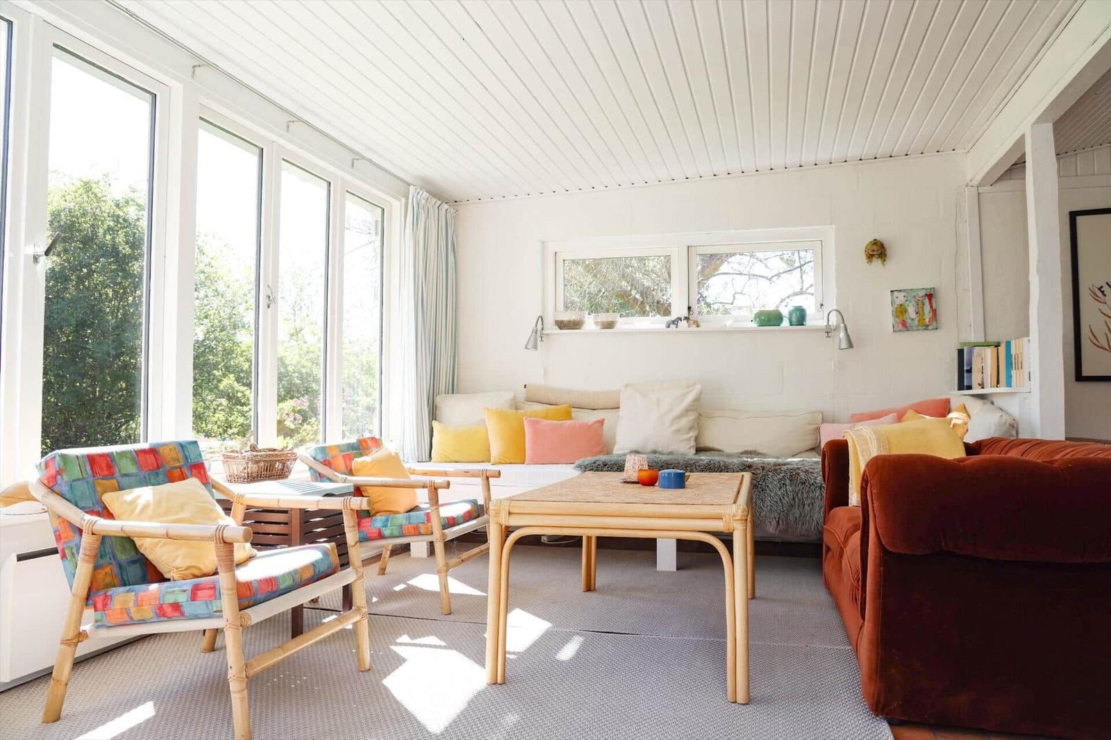 Wohnzimmer mit Sitzgelegenheiten, großem Fenster und Tisch. Holz- und Stoffmöbel.