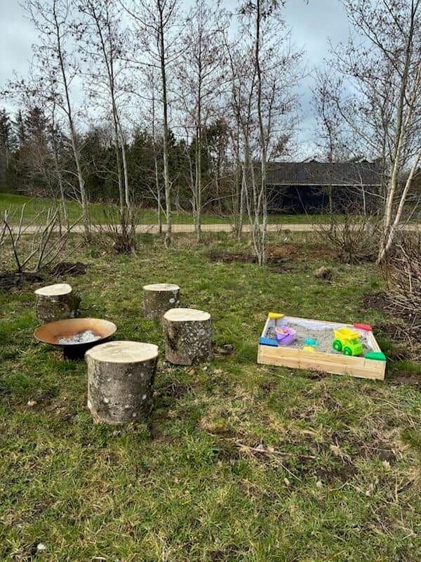 Außenbereich mit Holzstümpfen und Sandkasten für Kinder.