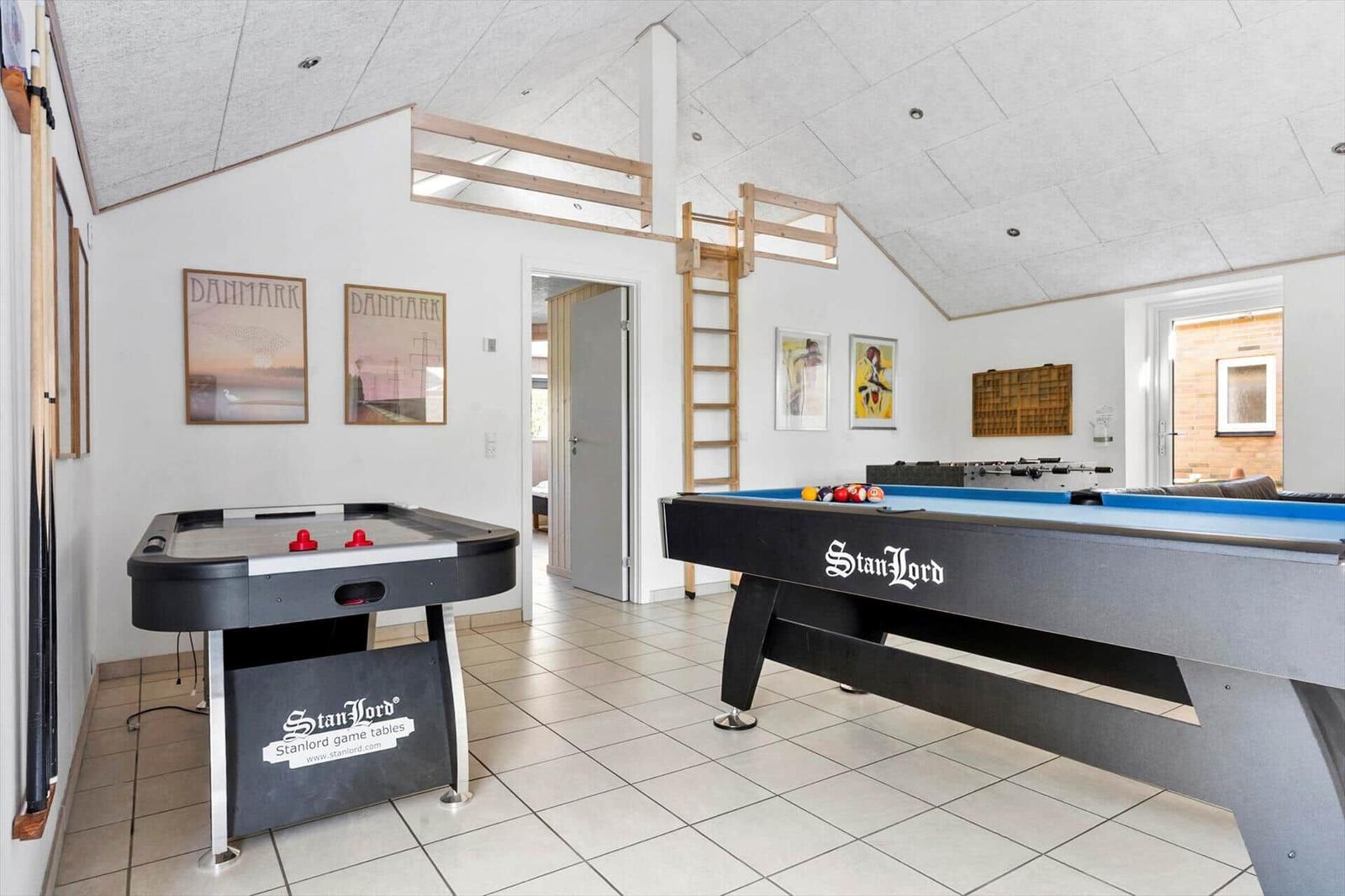 Raum mit Billardtisch und Airhockey-Tisch. An der Wand hängen Bilder.