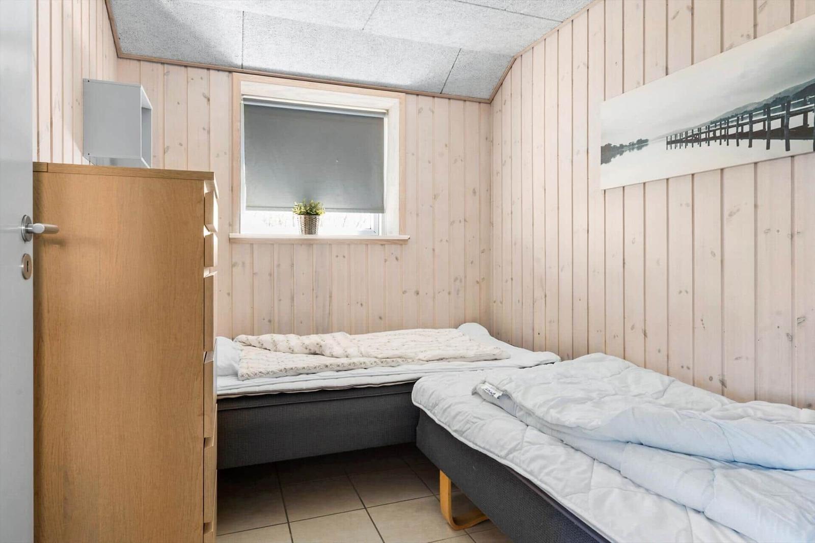 Zwei Betten in einem Raum mit Holzwand und Fenster.