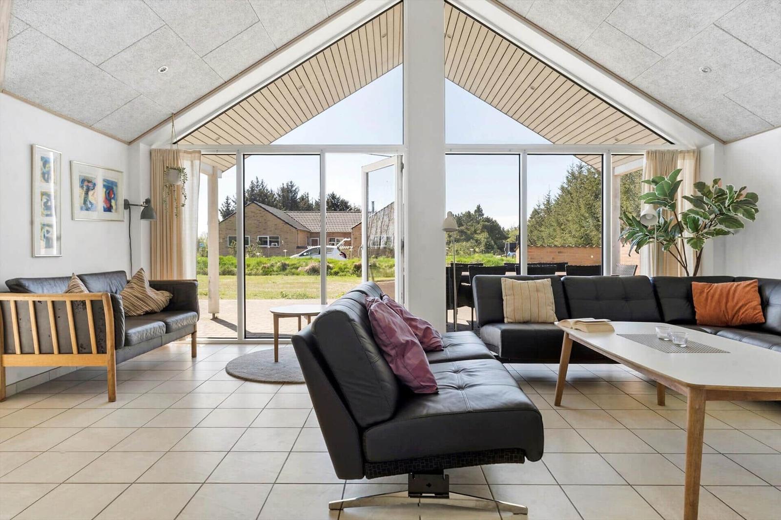 Large living room with black sofas, wooden furniture, and large window view.