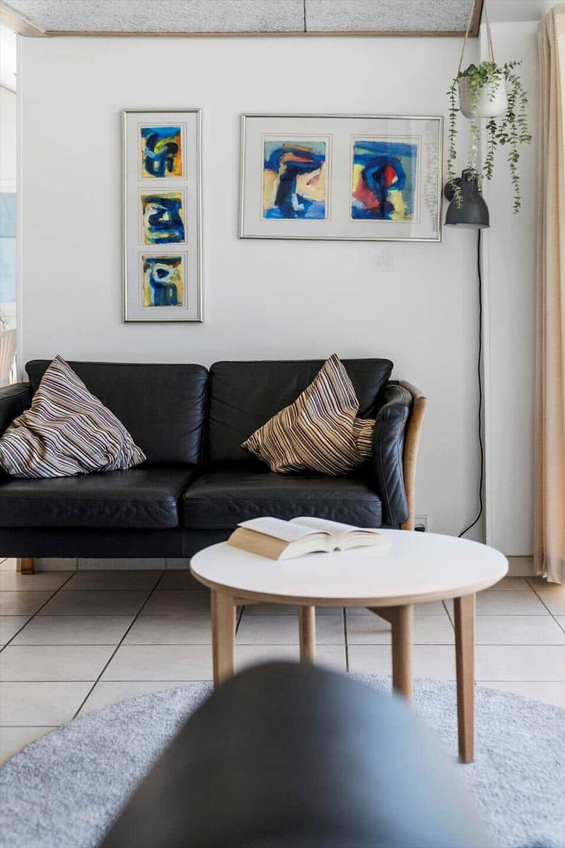 Black sofa with cushions, round table, and wall art.