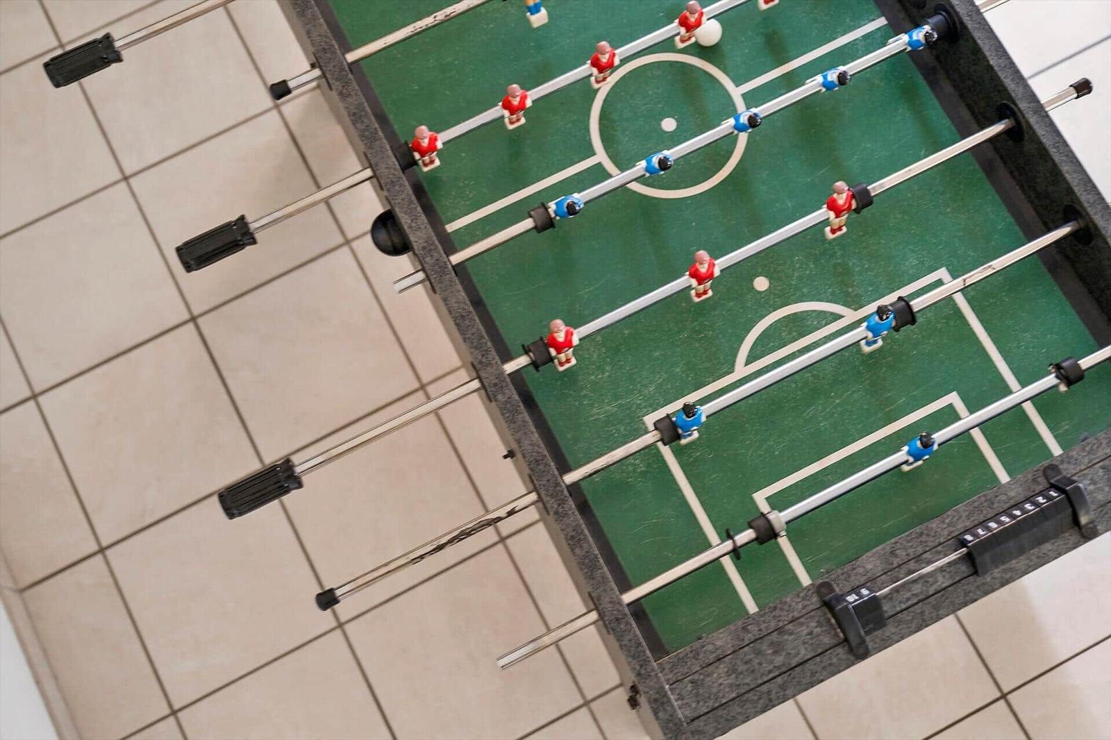 Foosball table with red and blue players on green field.