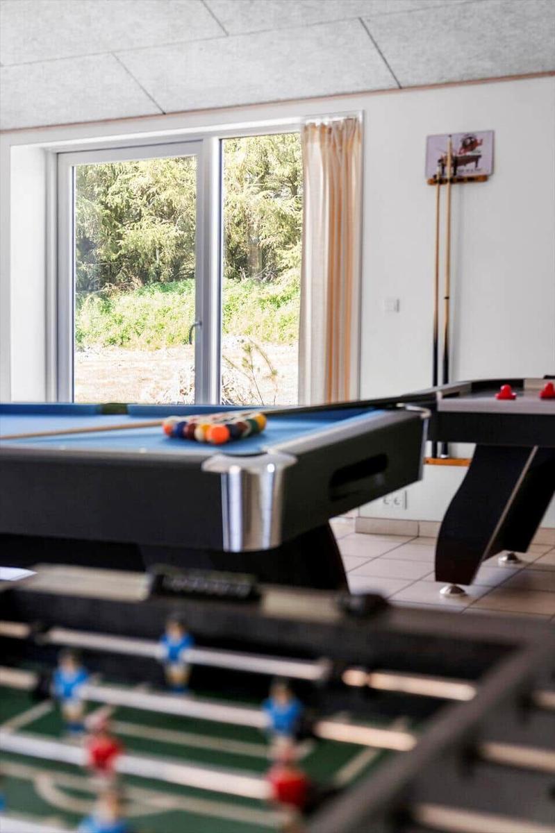Room with pool table, foosball table, and view of green landscape.