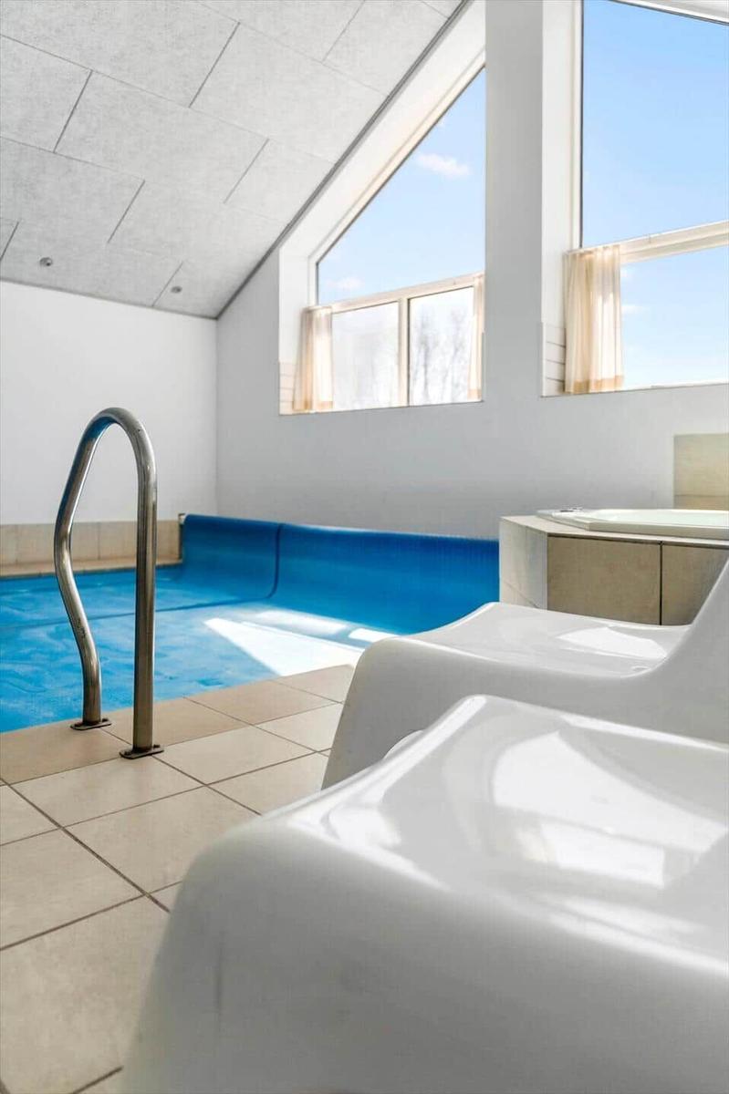 Indoor pool with wooden windows and white lounge