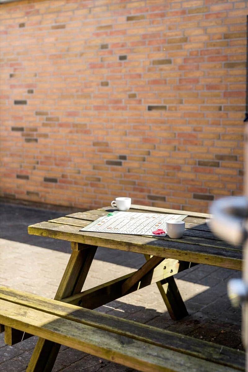 Wooden table with two mugs and game board in front of brick wall