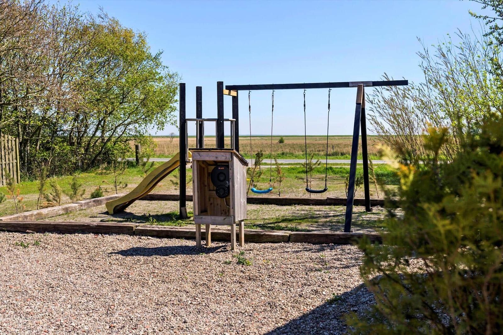 Childrens playground with slide and swings on gravel ground