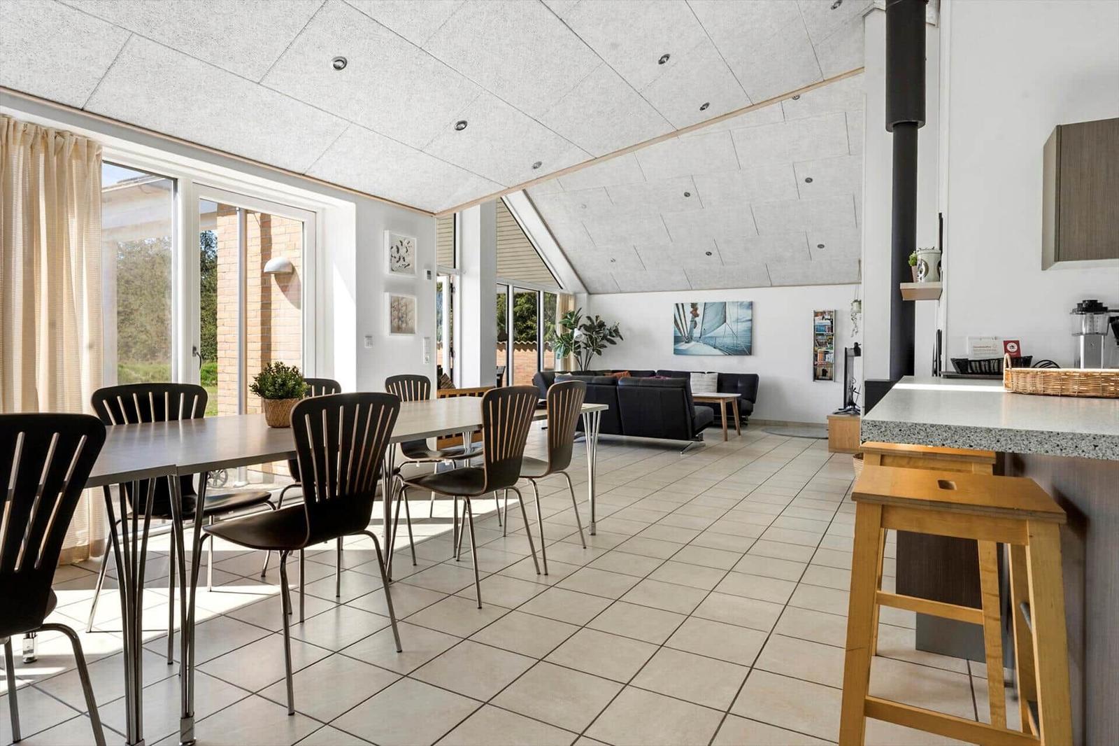 Large open space with dining area, living area, and kitchenette. Wooden and metal furniture.