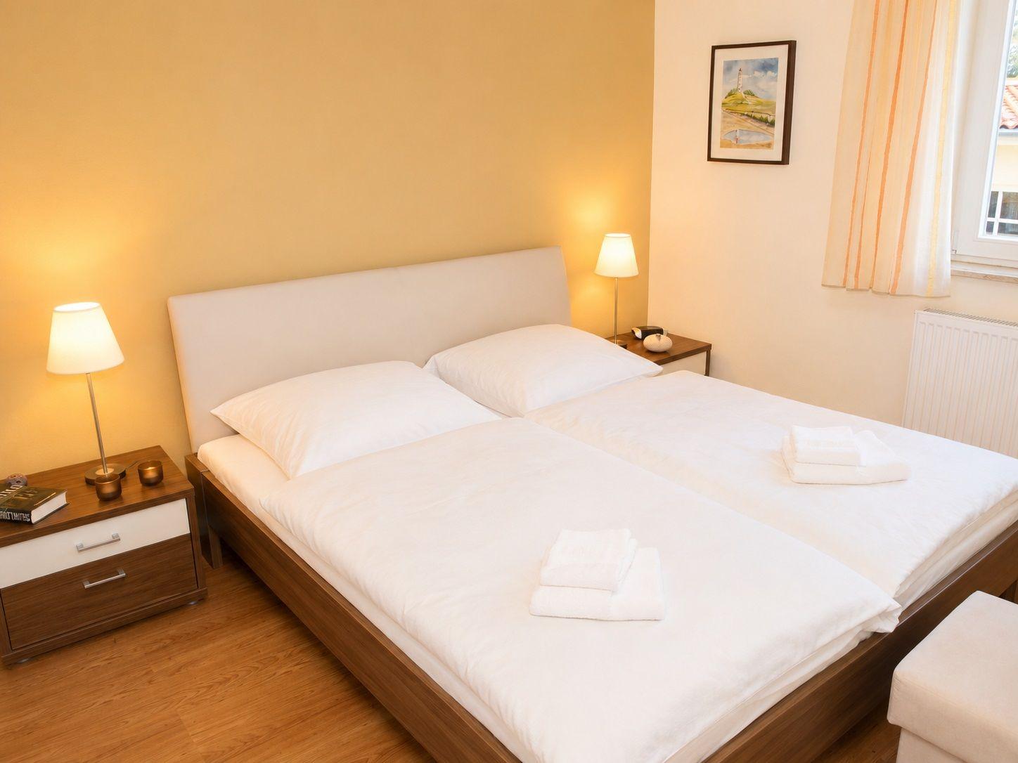 Ein Schlafzimmer mit Doppelbett, zwei Nachttischen und einem Fenster.