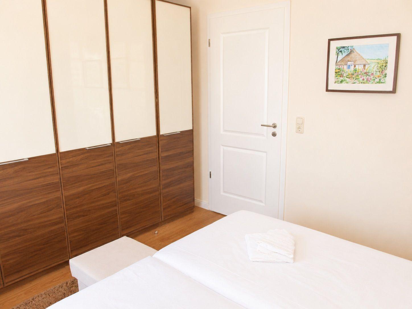 Schlafzimmer mit Bett, Kleiderschrank und Wandbild.