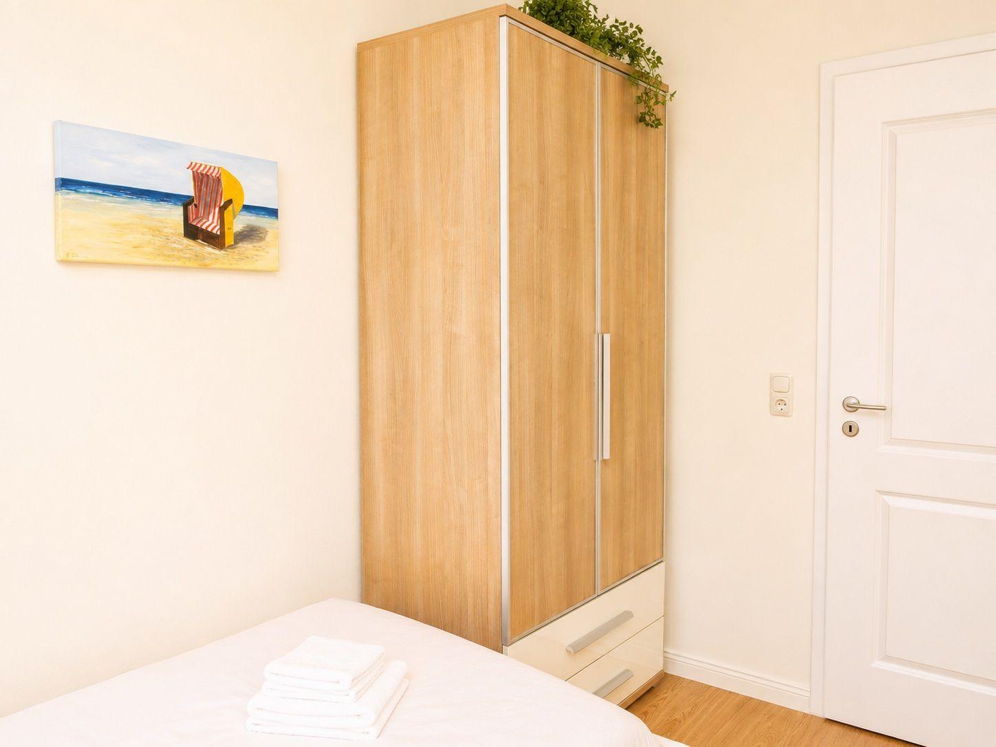 Schlafzimmer mit Bett, Kleiderschrank und Wandbild.