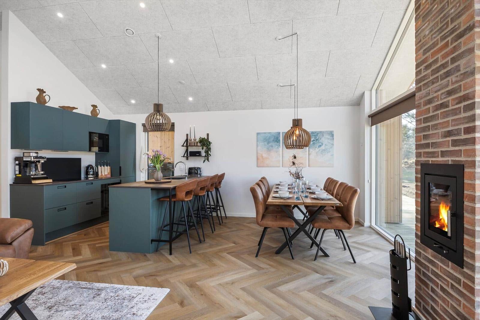 Küche mit Essbereich, Holzboden und Kamin. Moderne Einrichtung mit braunen Stühlen.