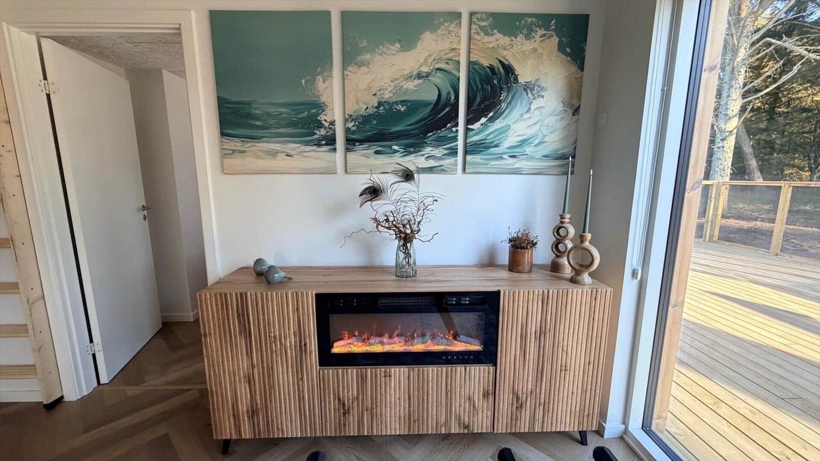 Holzschrank mit eingebauter Feuerstelle unter Wandbildern von Wellen.