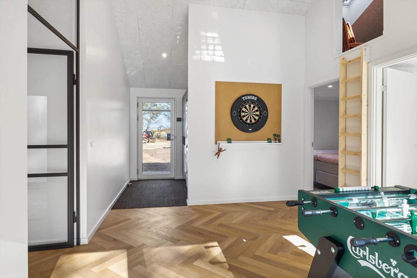 Raum mit Dartboard, Foosballtisch und Schlafbereich mit Leiter.