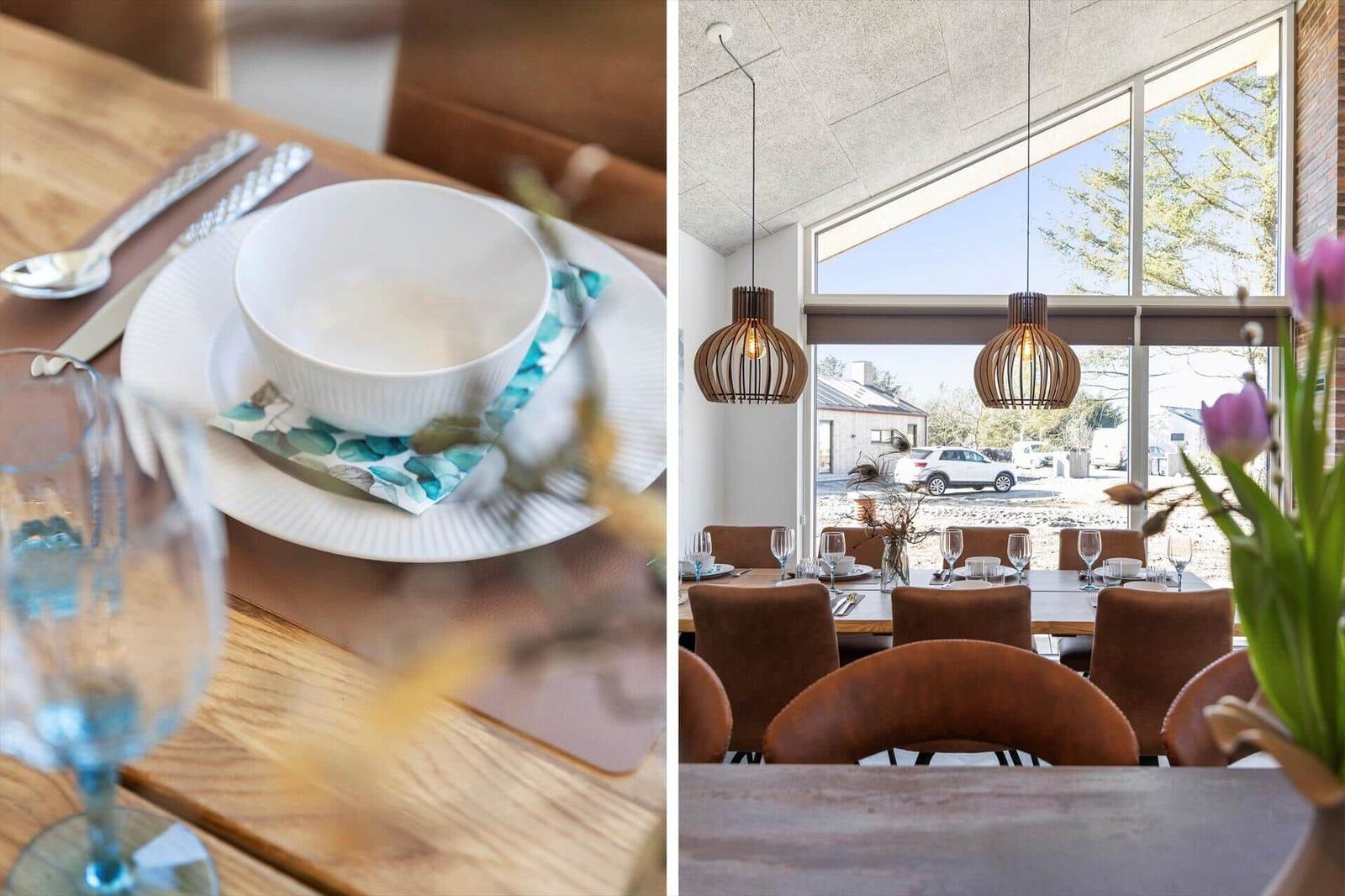 Esszimmer mit Holztisch, braunen Stühlen und großen Fenstern. Tisch gedeckt mit Schüssel und Glas.
