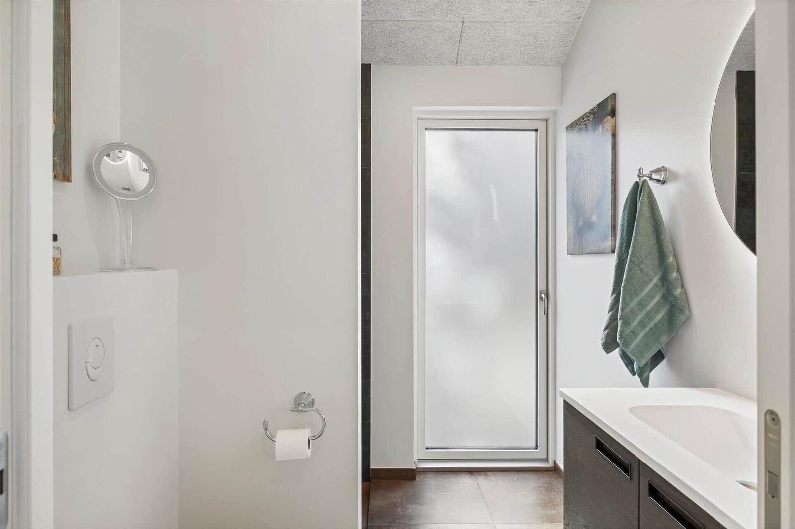 Badezimmer mit Waschtisch, Spiegel und Toilettenpapierhalter