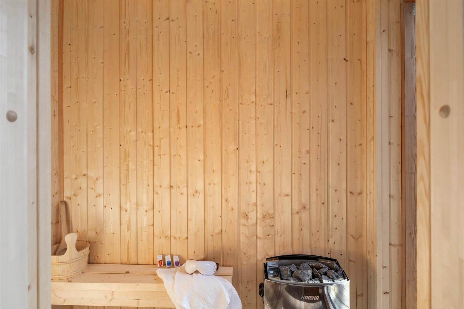 Sauna mit Holzwand, Sitzbank, Körbchen und Heizung.