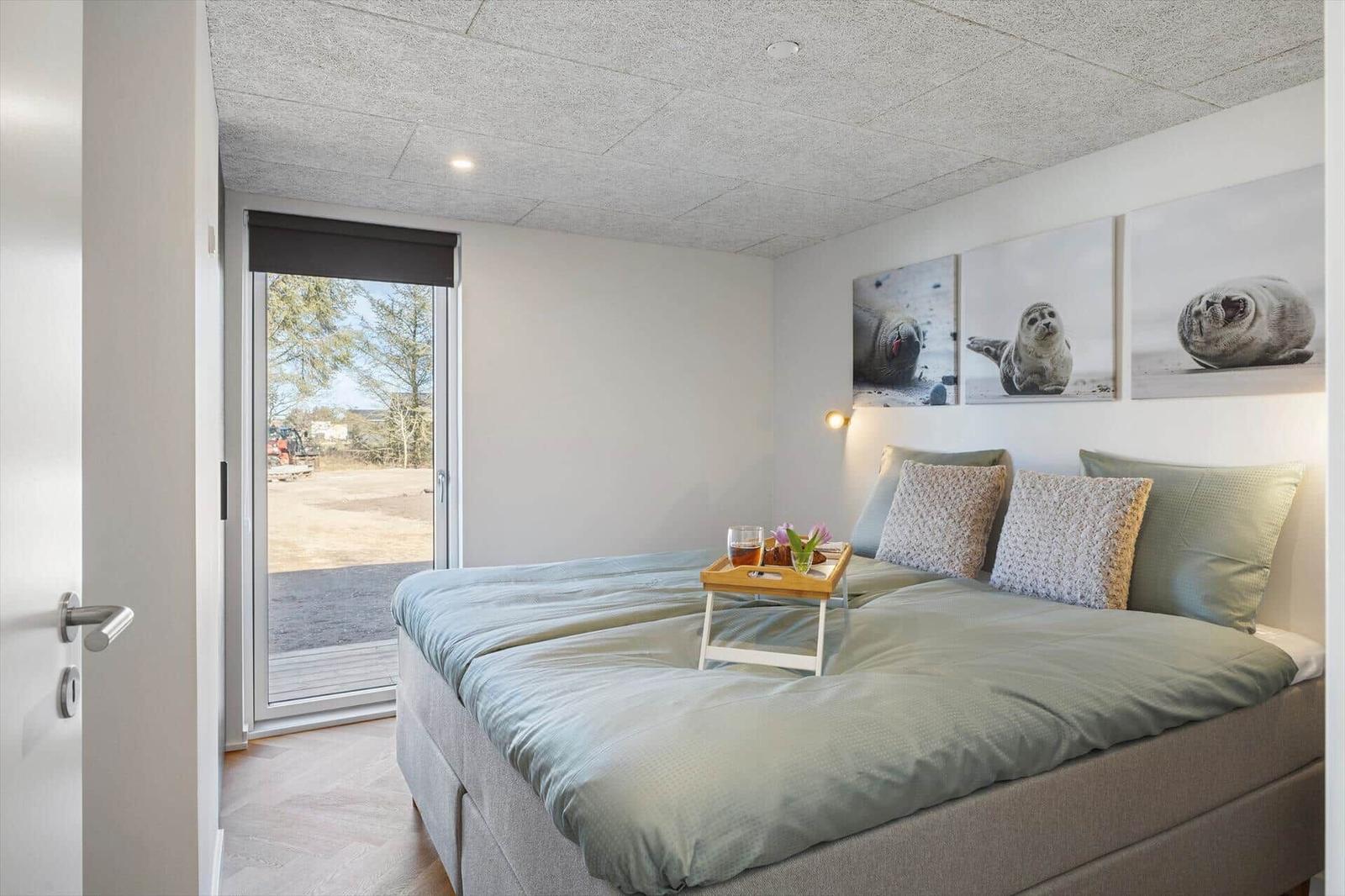 Schlafzimmer mit Bett, Fenster und Wandbildern von Seehunden.
